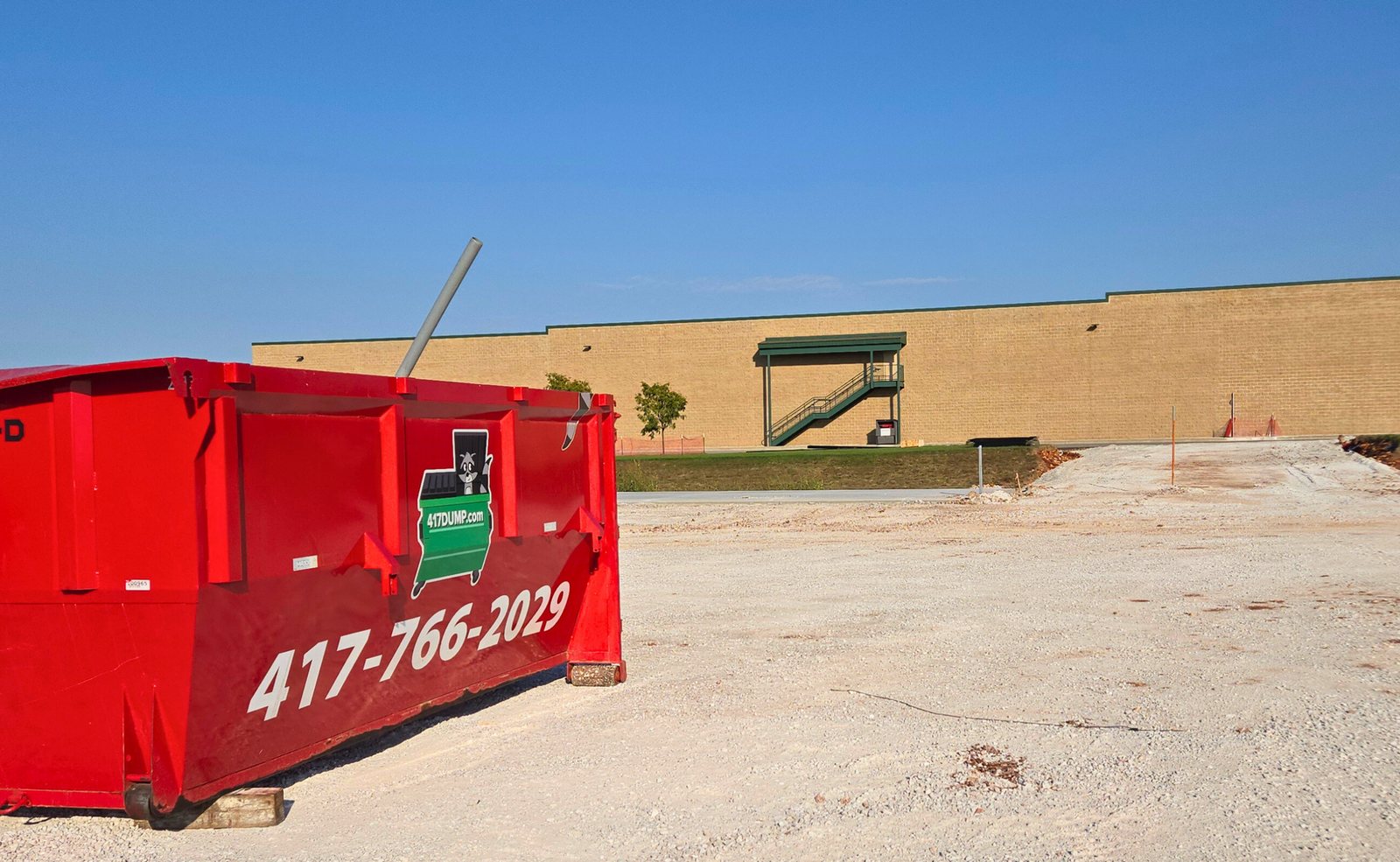 A red 417 Dumpster Rental roll-off holding broken concrete on a job in Springfield, MO